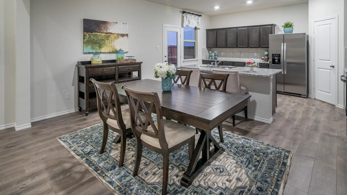 The dining area features engineered wood flooring, an accent rug, and a dining table with chairs