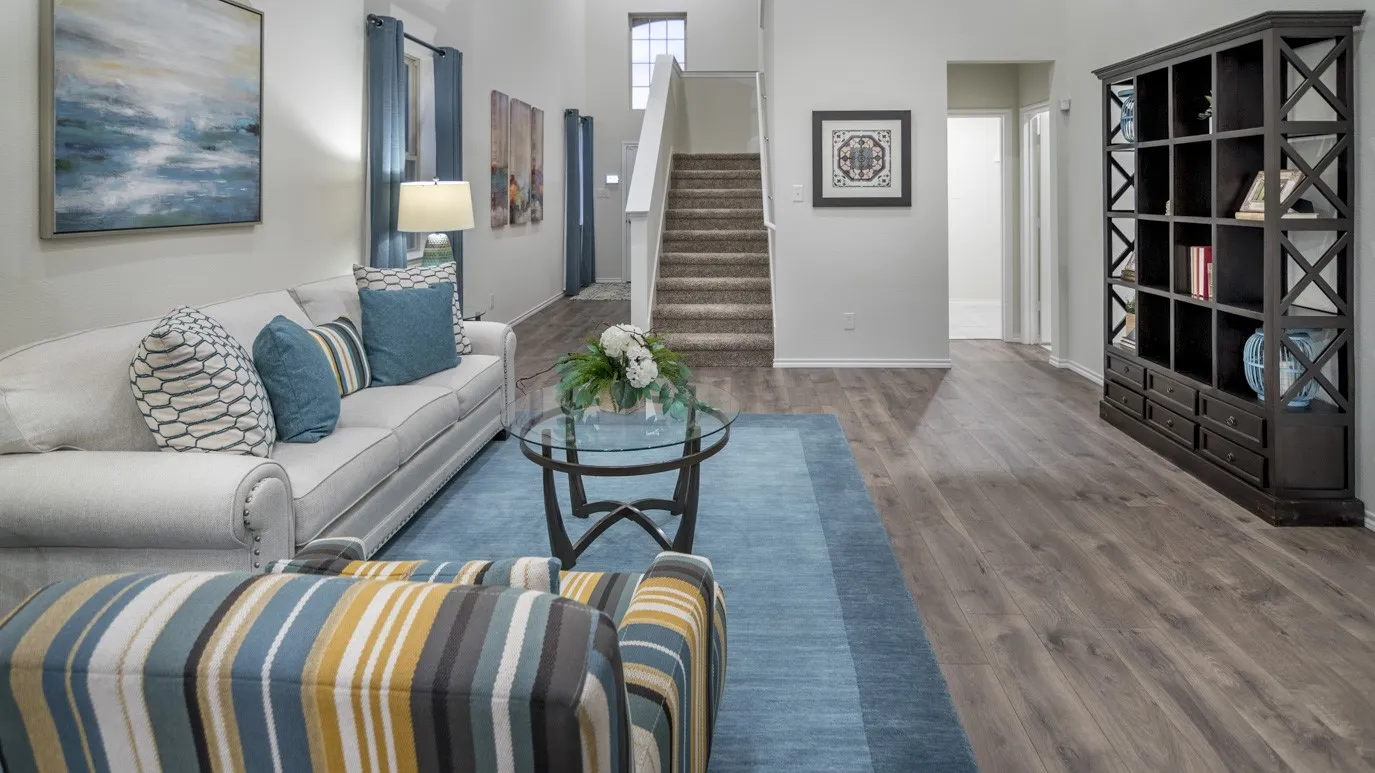 The inviting living space features wood-style flooring and a staircase with carpeted treads