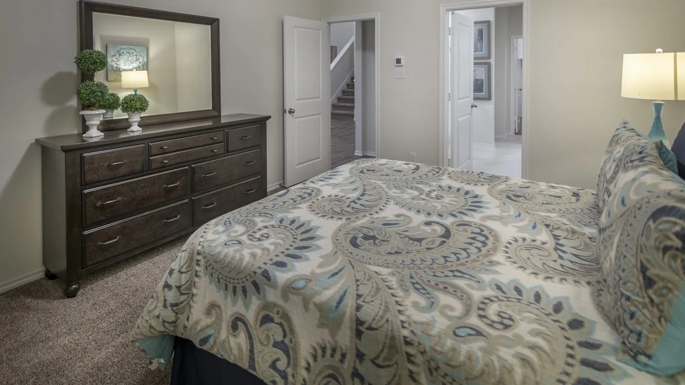 The bedroom features carpeting and light-colored walls, with an open doorway providing a glimpse of a hallway
