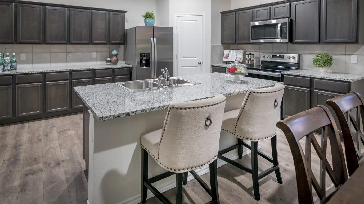 The kitchen features extensive dark wood cabinetry, light-colored granite countertops, and stainless steel appliances