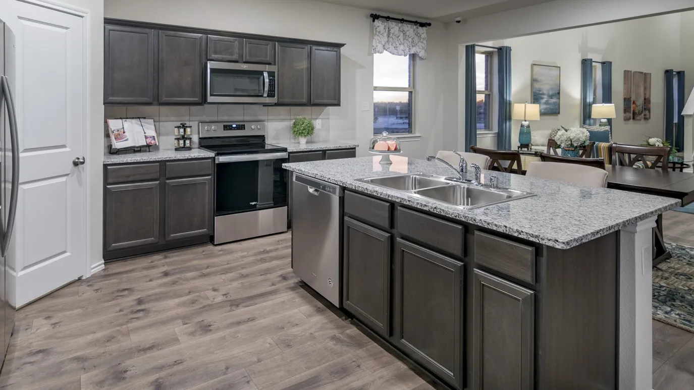 The kitchen features dark wood cabinetry, stainless steel appliances, granite countertops, and a double basin sink