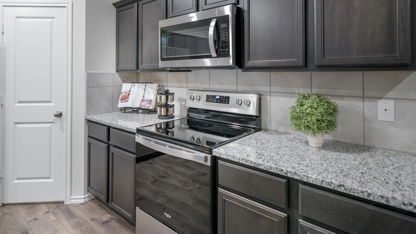 The kitchen features dark wood cabinetry, granite countertops, and stainless steel appliances including a microwave and range