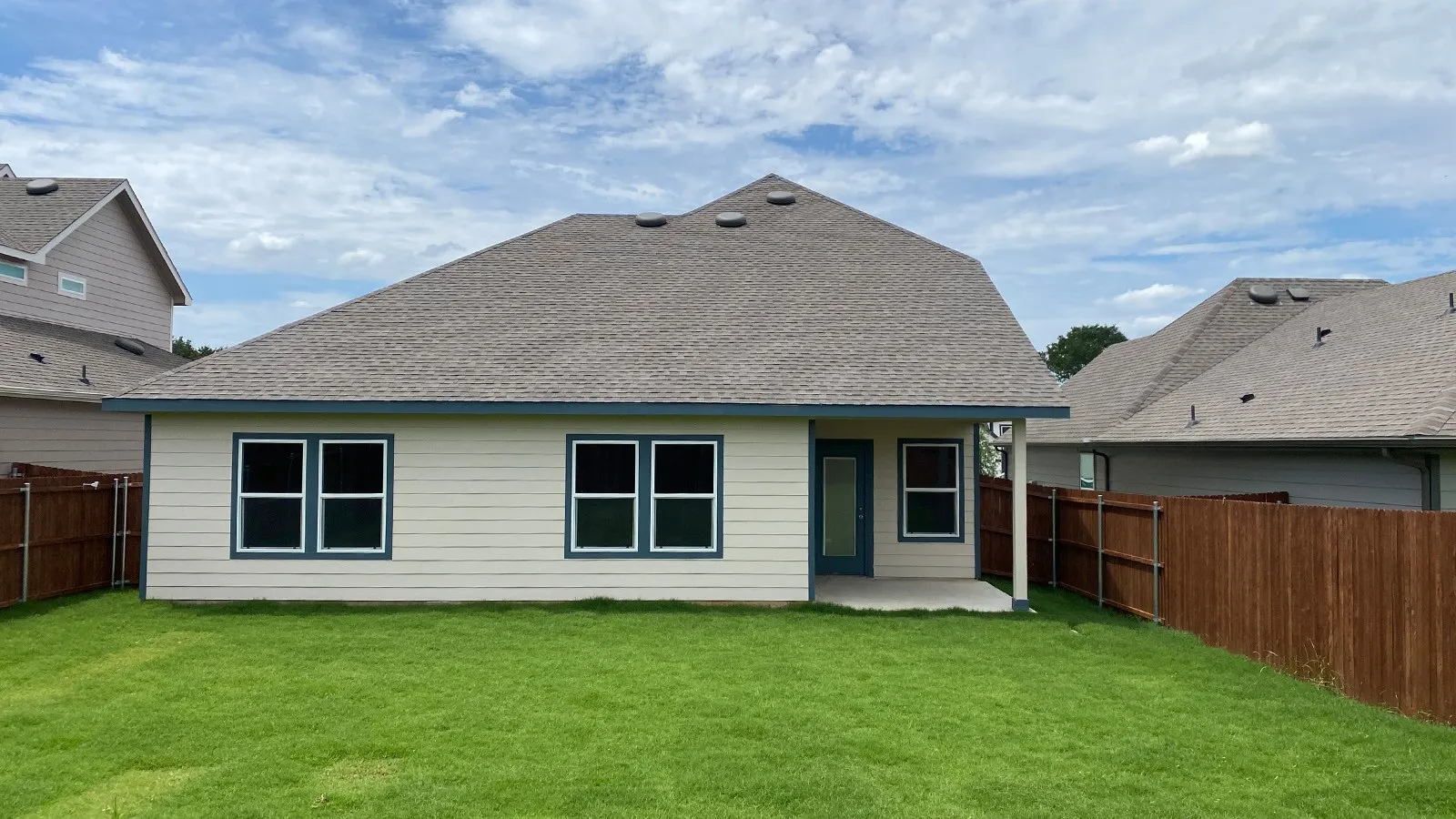 Expansive backyard featuring a manicured lawn, a concrete patio, and a wood privacy fence