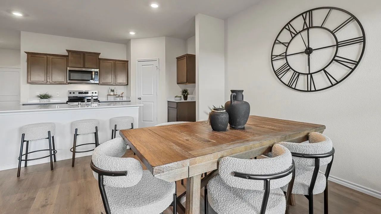 Open-concept living space featuring a dining area with wood flooring and a kitchen with brown cabinetry, stainless steel appliances, and a breakfast bar