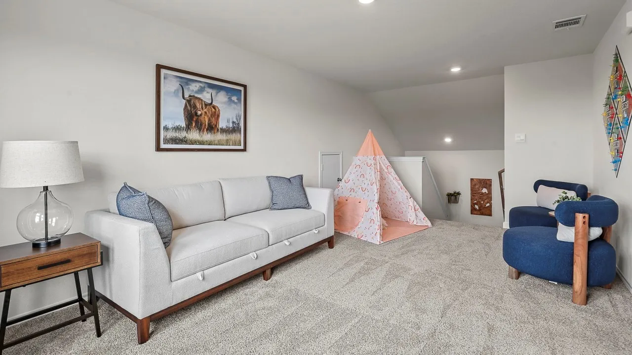 This versatile space features light gray carpet flooring, recessed lighting, and a neutral wall color