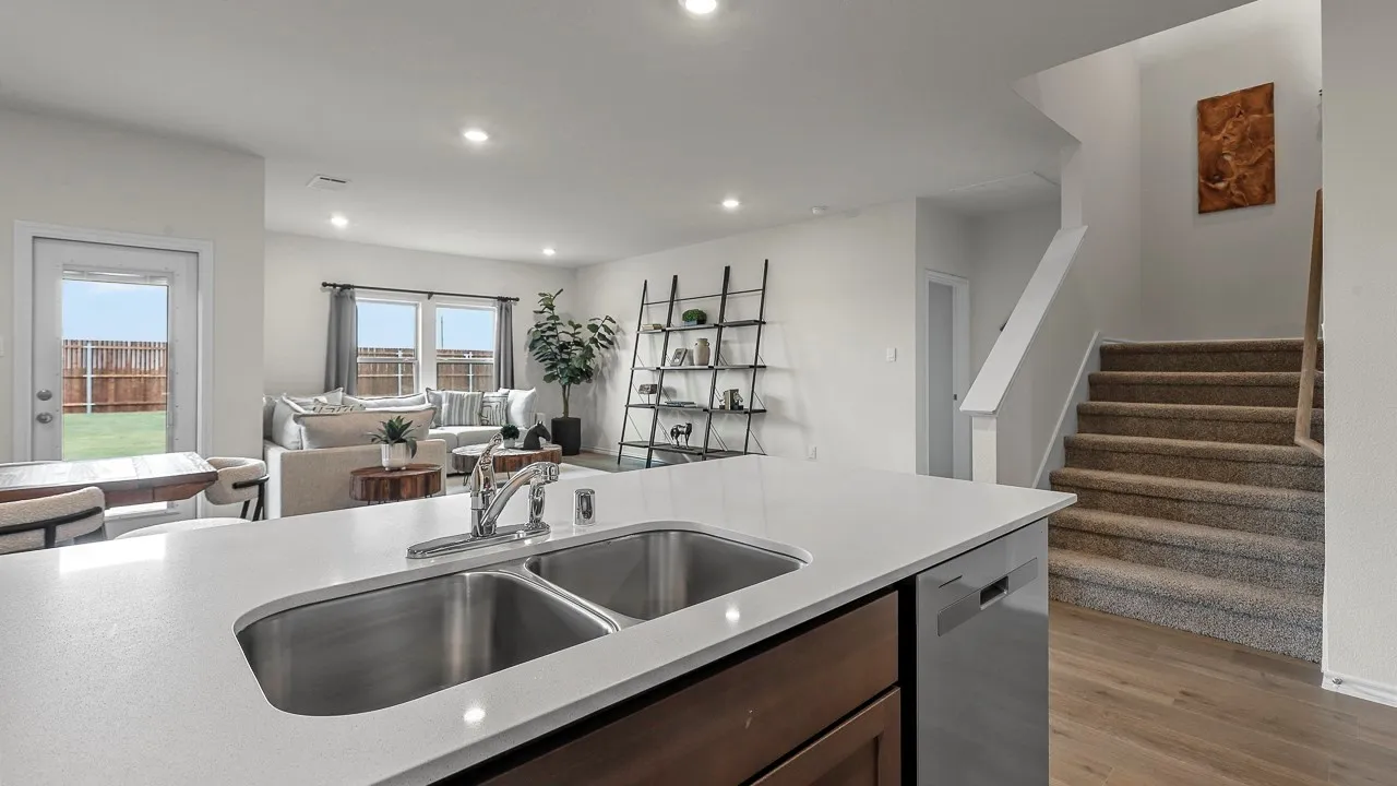 The property features a kitchen with a double basin sink and a dishwasher, with a view of the living area