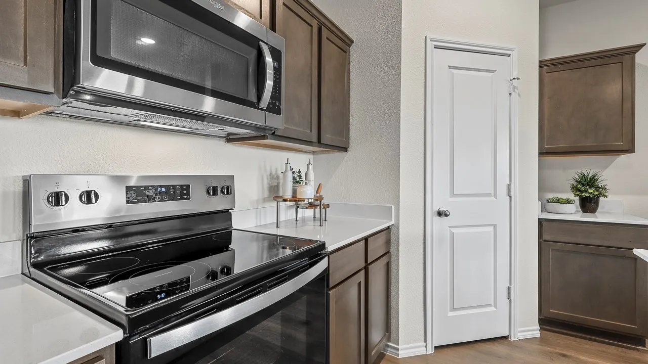 The kitchen features a stainless steel microwave and electric range with a glass cooktop, alongside white countertops and brown cabinetry