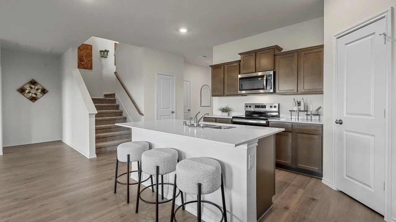 The property features an open-plan kitchen with a central island and a staircase with carpeted steps