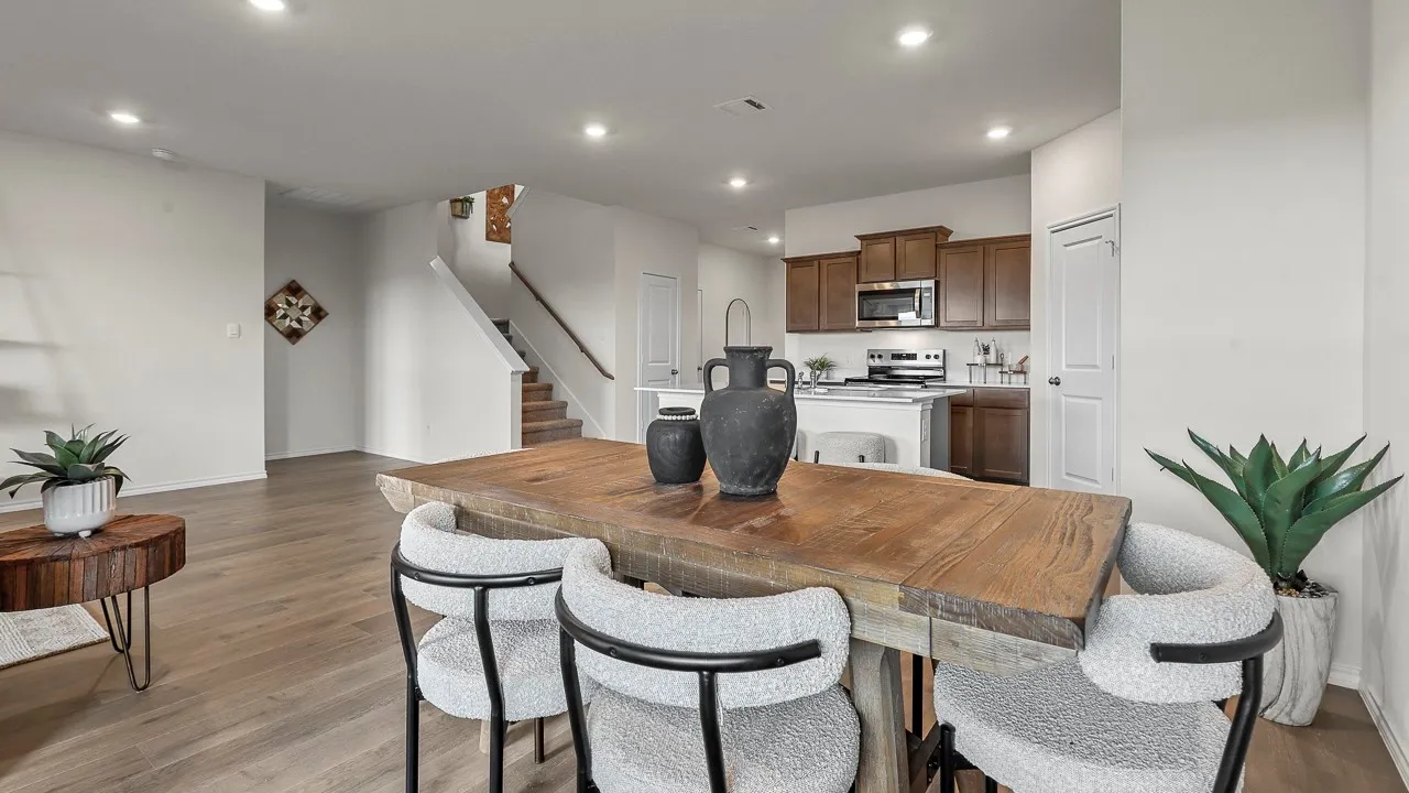Open concept living space featuring recessed lighting, light-toned flooring, and a staircase with a wooden handrail