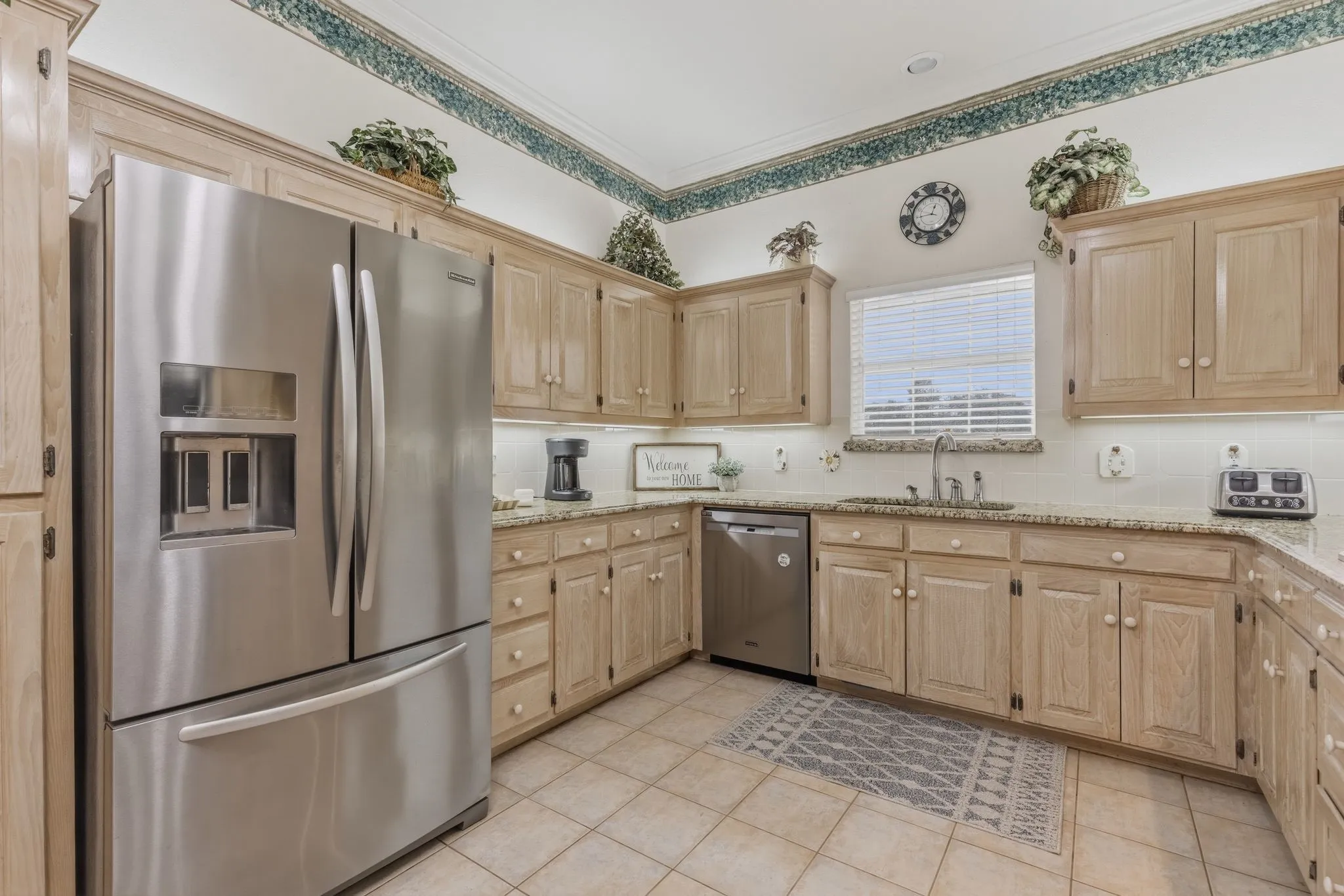 The kitchen features light-colored cabinetry, stainless steel appliances, and granite countertops