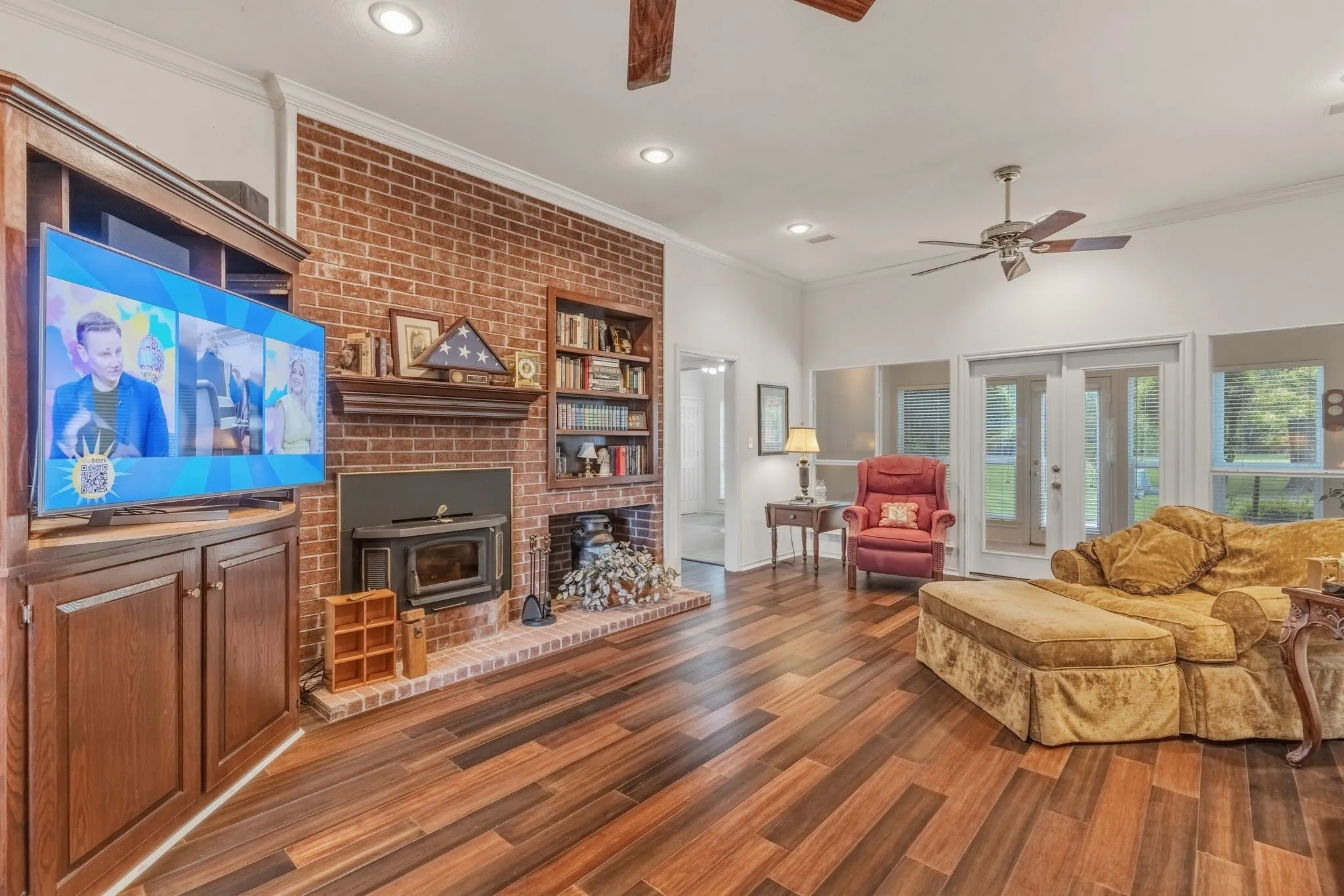 This living space features rich hardwood flooring, a brick accent wall with a fireplace, and built-in shelving
