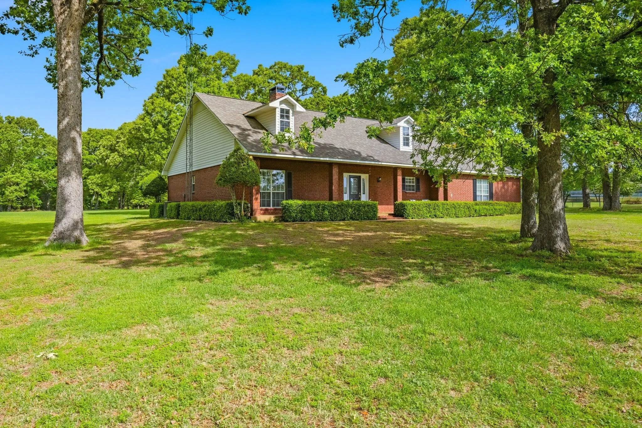 The property features a brick exterior with white siding, a dark roof, and dormer windows