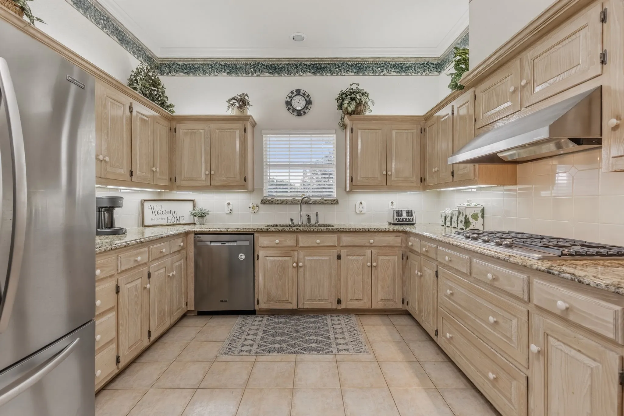 Well-appointed kitchen featuring light-toned wooden cabinetry, granite countertops, and tile flooring