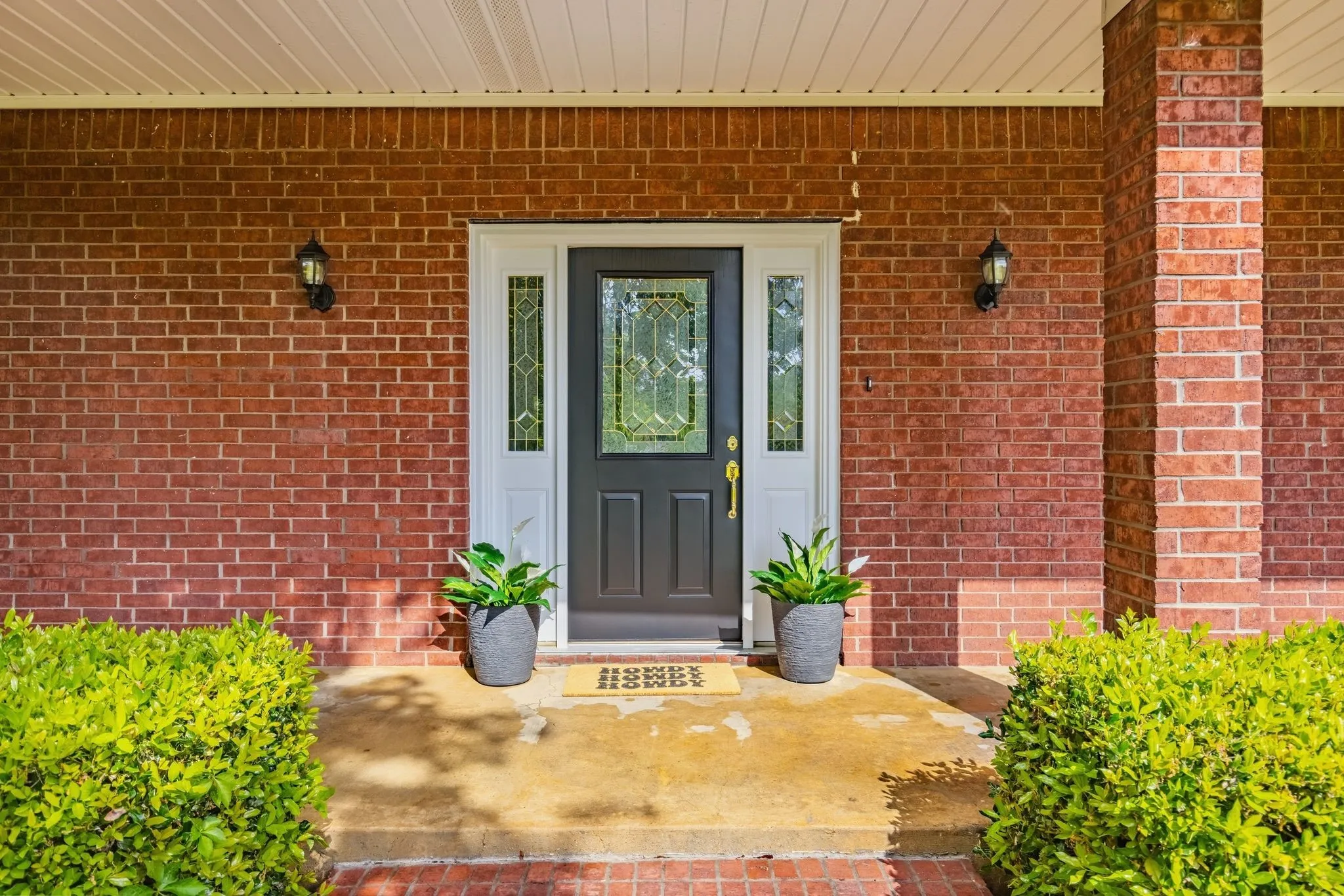 The property features an inviting brick facade with a dark front door, accented by decorative glass panels and sidelights