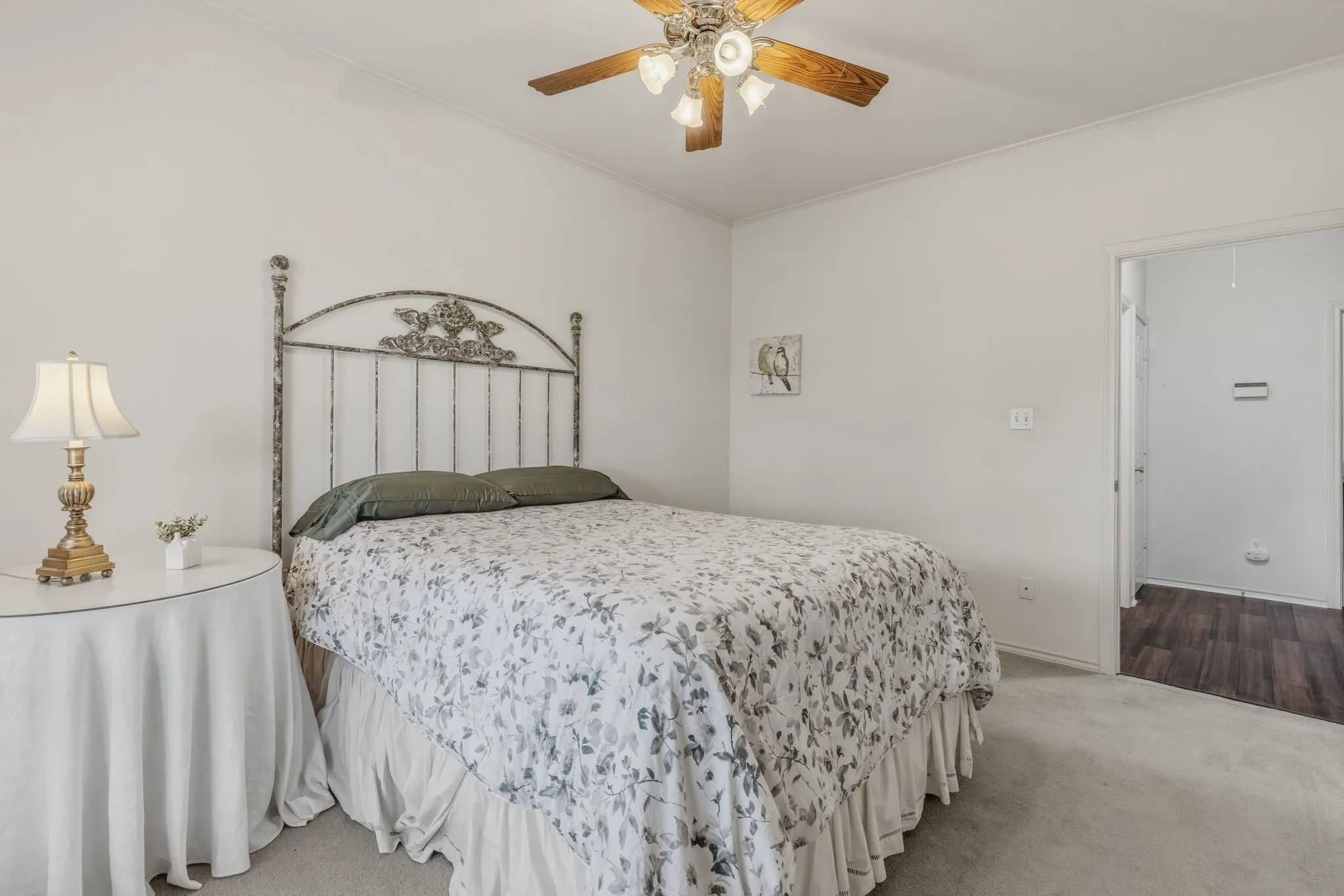 This room features a ceiling fan with a light fixture, carpeted flooring, and white walls