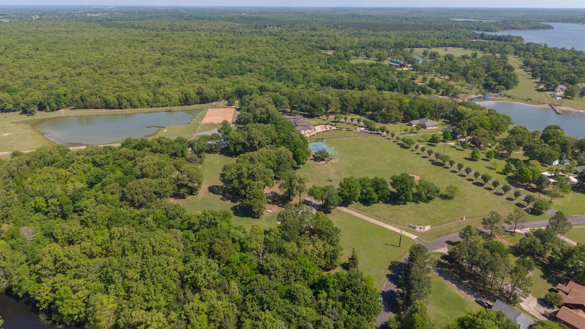 Aerial view showcasing expansive green spaces, mature trees, and a visible body of water