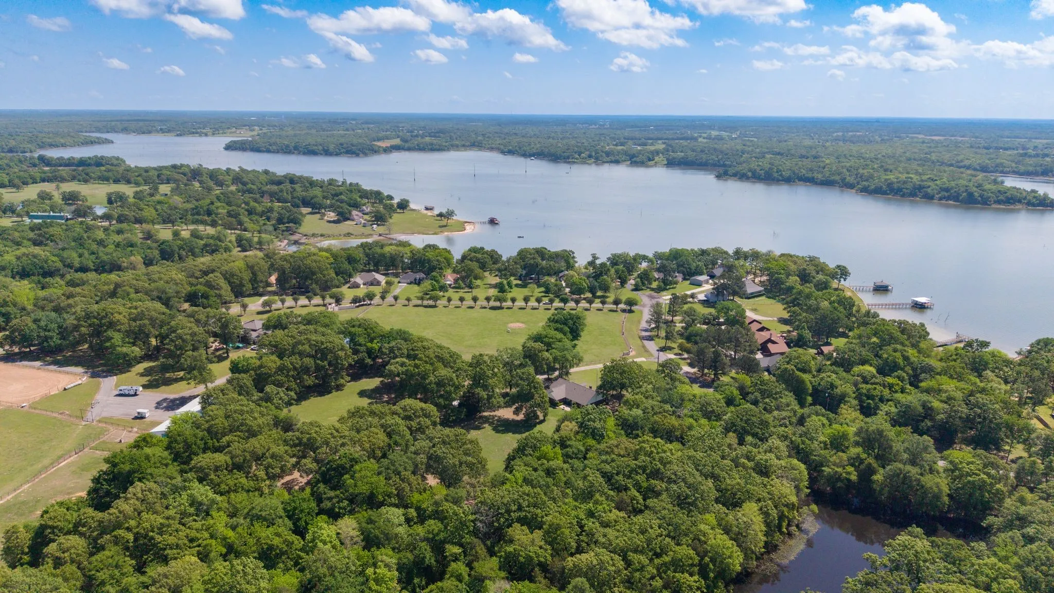 Aerial view showcasing the expansive lake, surrounding lush green trees, and clear blue skies
