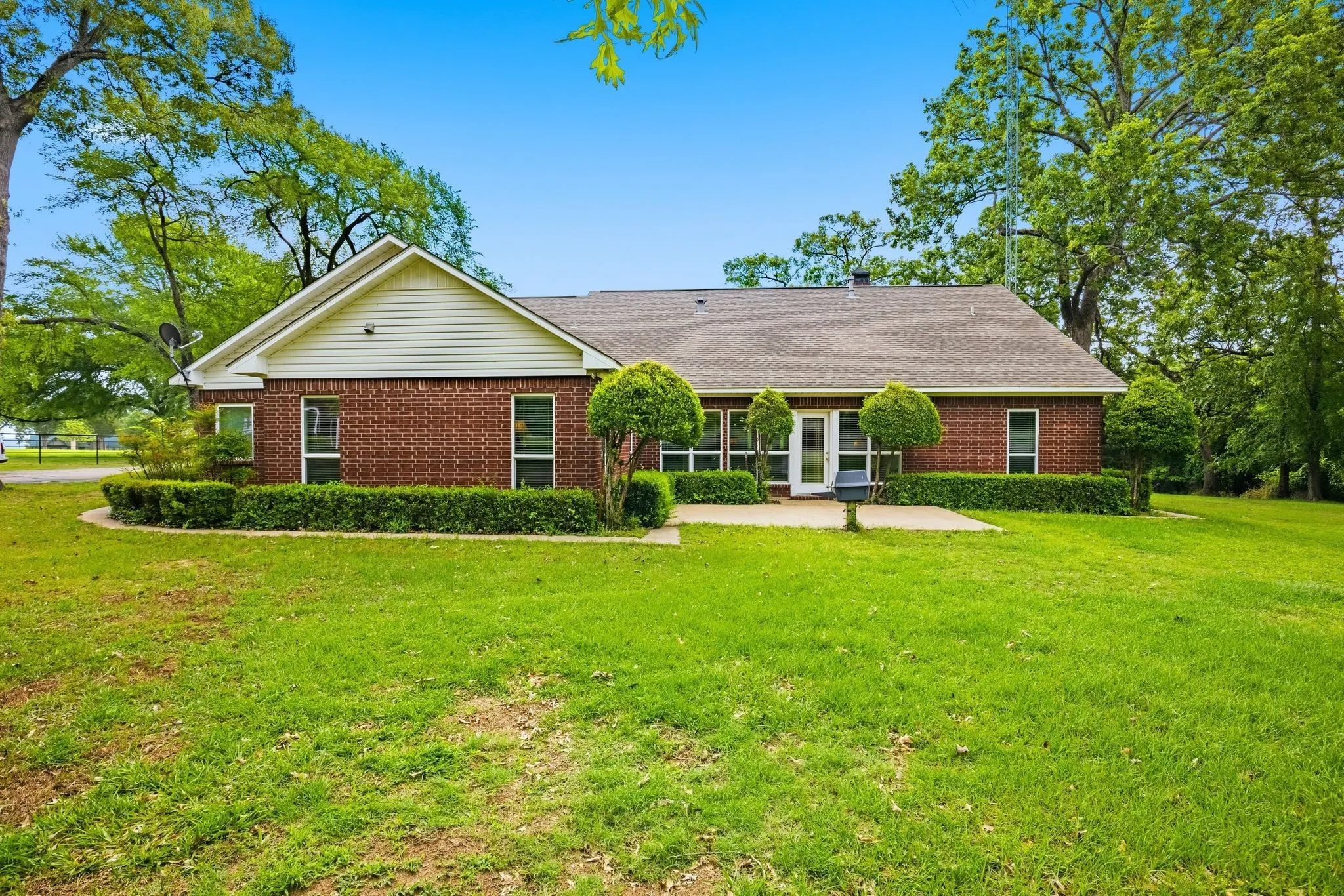 The property features a brick exterior with white siding, a shingled roof, and a well-maintained lawn