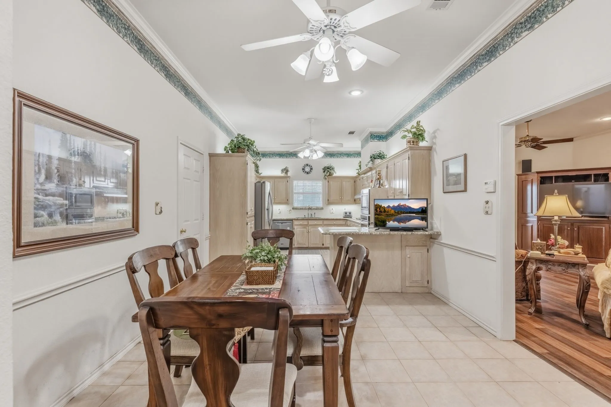 This dining area features tile flooring, a ceiling fan with integrated lighting, and crown molding