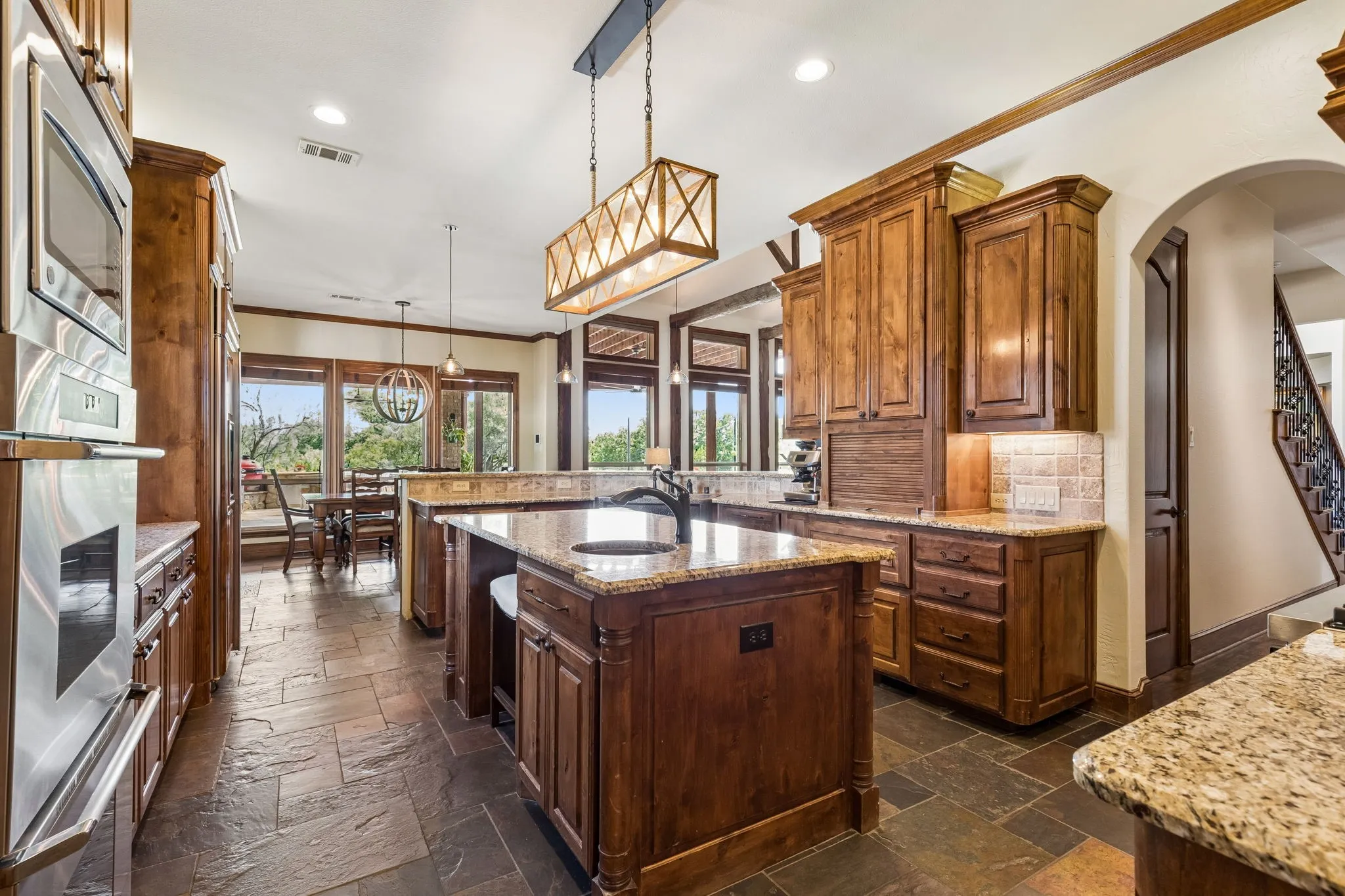 The kitchen features rich wood cabinetry, granite countertops, and a central island with an integrated sink