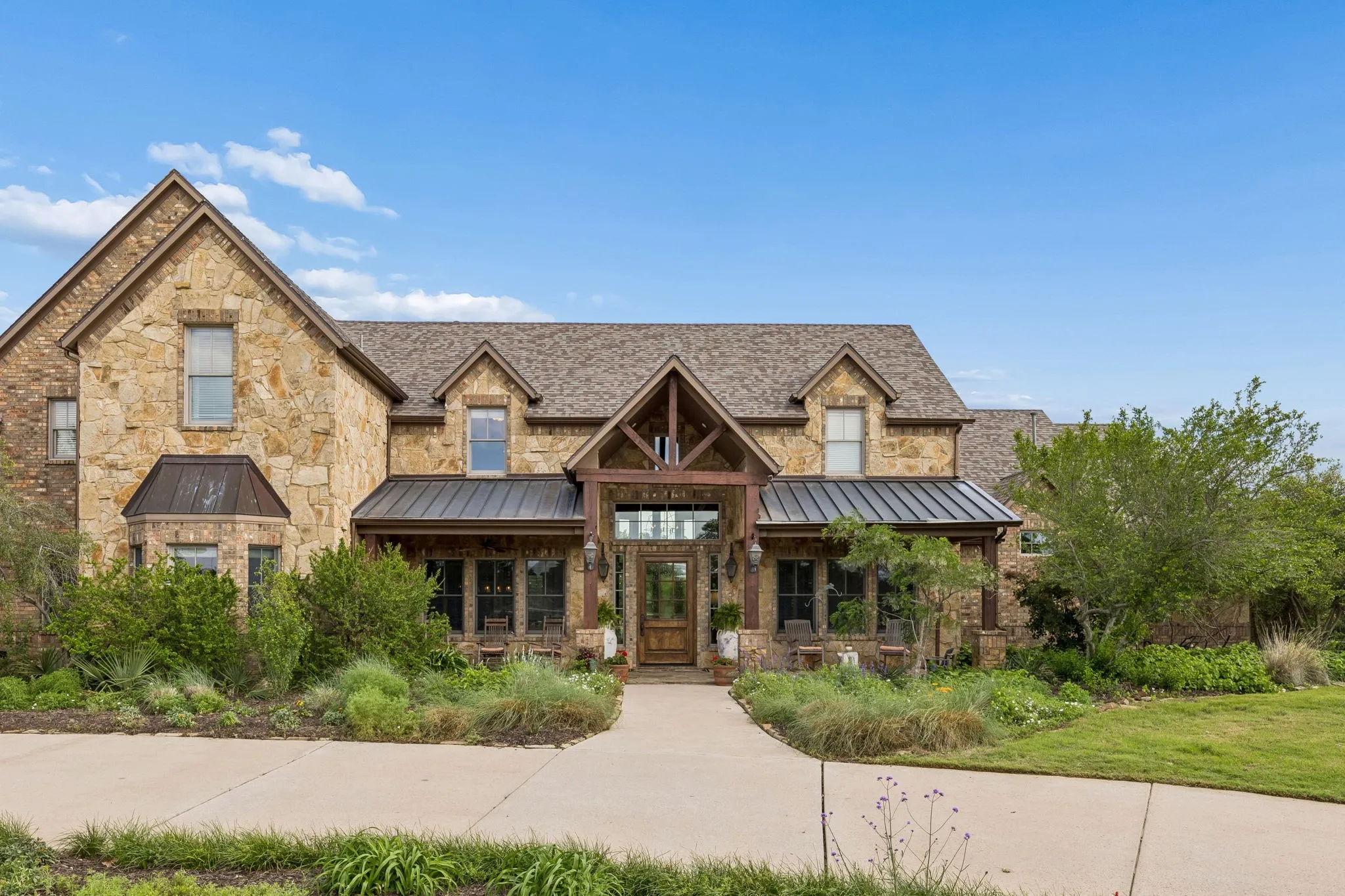The property features an appealing stone facade, a multi-gabled roof, and a welcoming covered porch entry