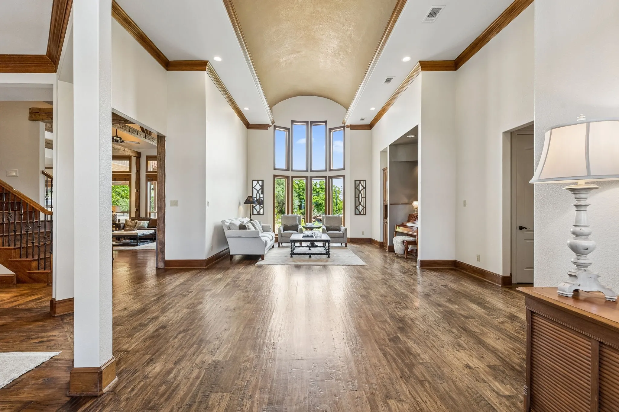 Expansive open-concept living area featuring high vaulted ceilings, large windows, and rich wood flooring
