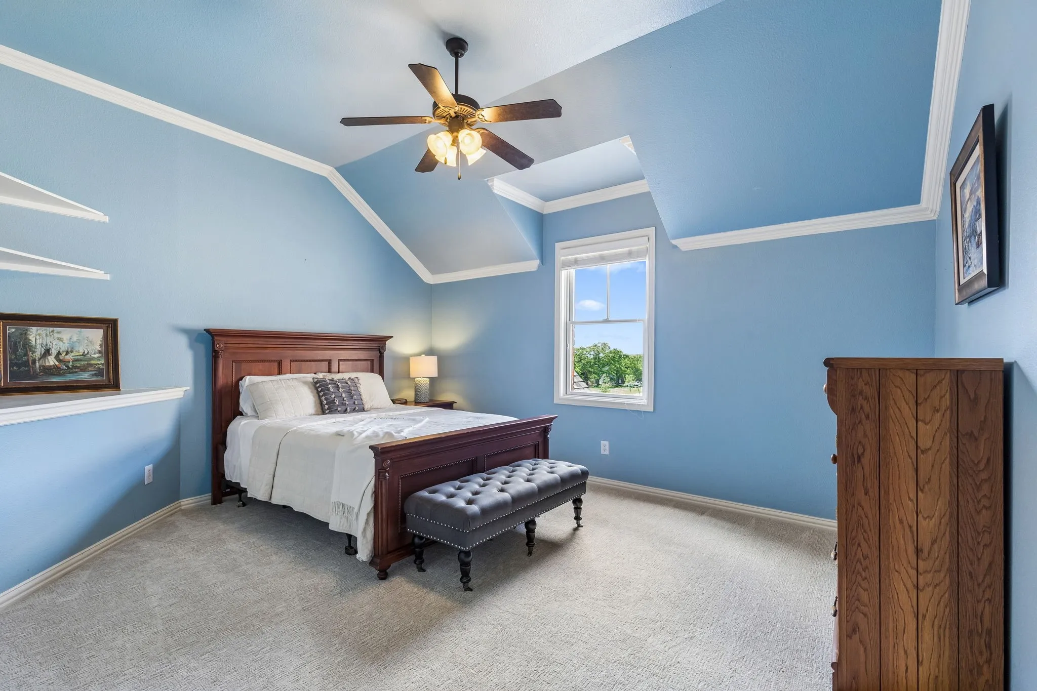 This room features light blue walls, a light-colored carpet, and a window providing natural light and views of greenery