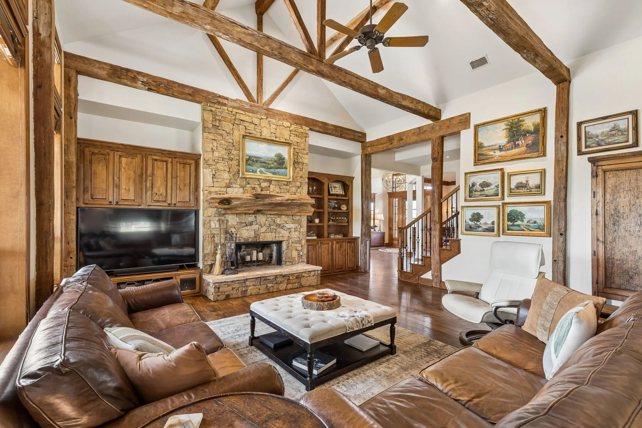 Living area featuring vaulted ceilings with exposed wood beams, a stone fireplace, and hardwood floors