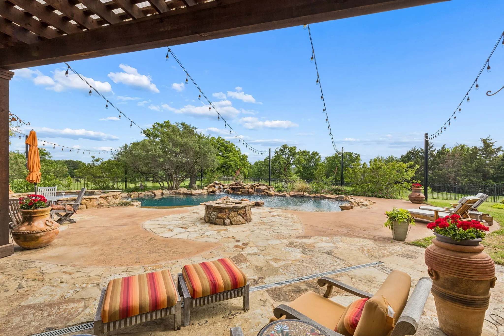 The property features a spacious outdoor patio with flagstone and concrete paving, a swimming pool with a rock waterfall, and a stone fire pit