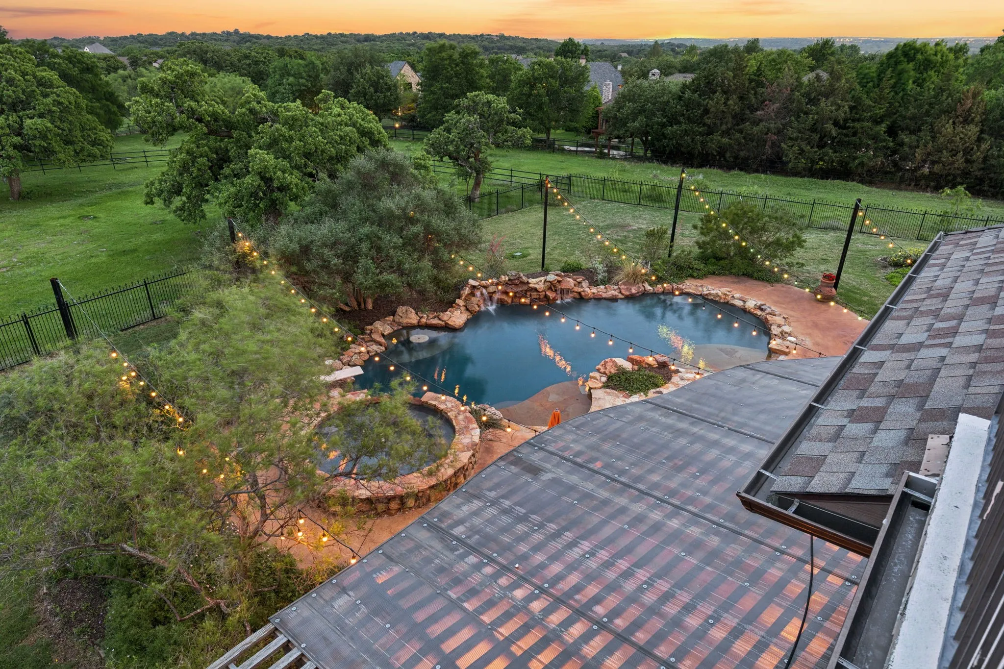 The property features a swimming pool with a stone surround, string lights, and a surrounding lawn area