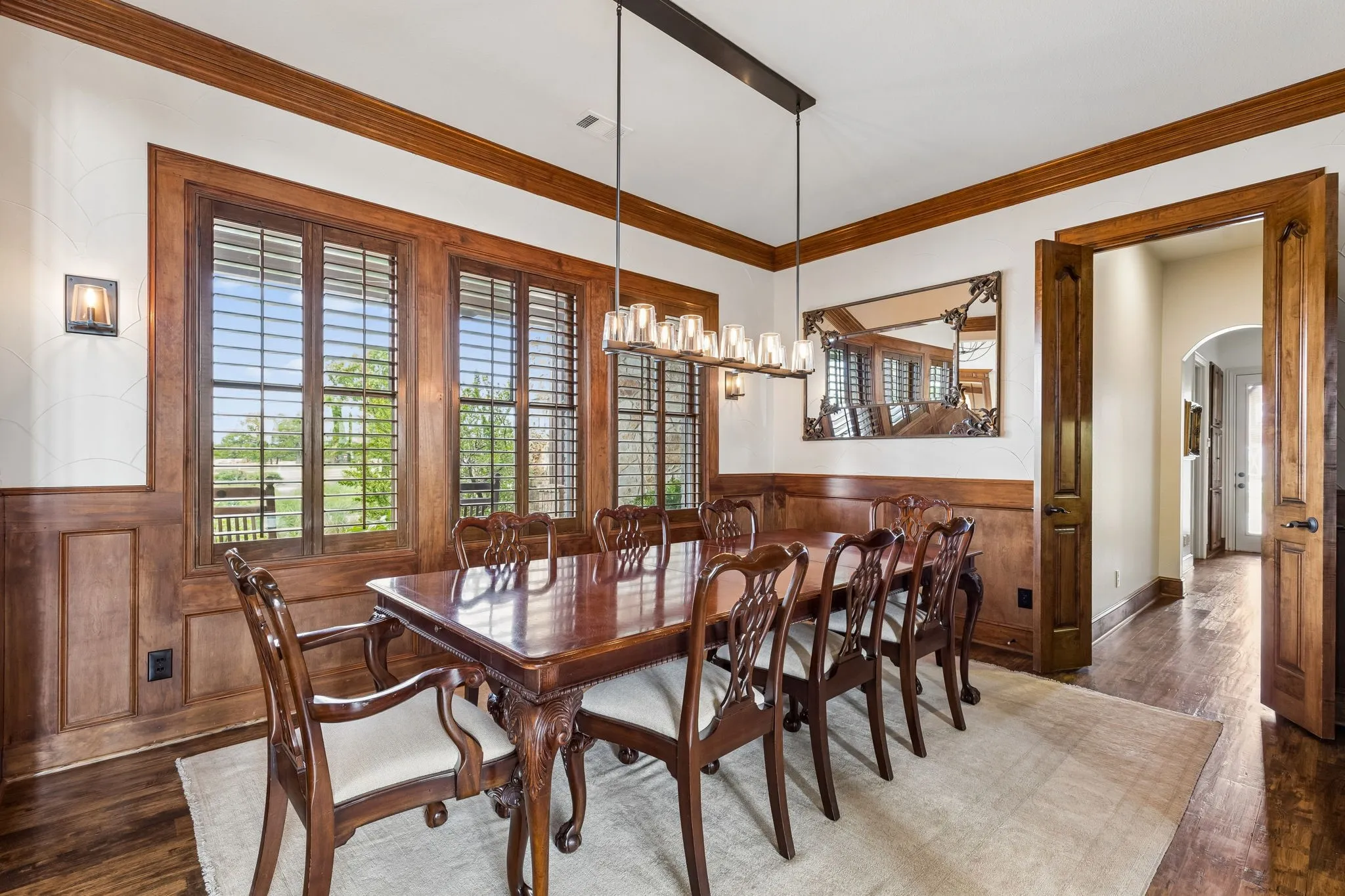 This dining area features extensive wood paneling, wood flooring, and large windows with wooden shutters