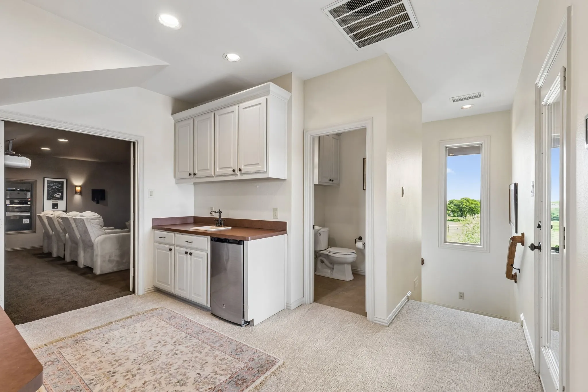 The property features a dedicated beverage station with a sink, white cabinetry, and an undercounter refrigerator