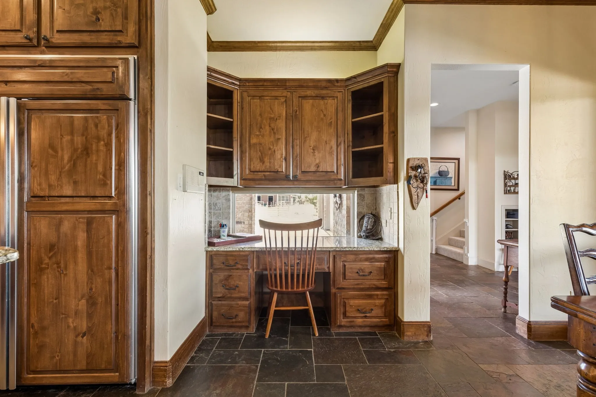 This property features a built-in desk area with wood cabinetry, granite countertops, and a tiled backsplash