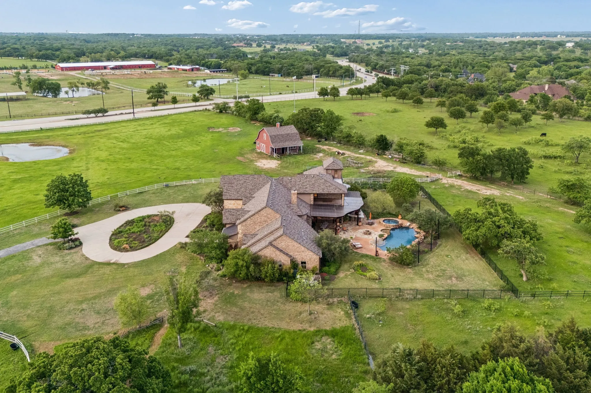The property features an extensive green lawn with mature trees, a circular driveway, and a swimming pool with a spa