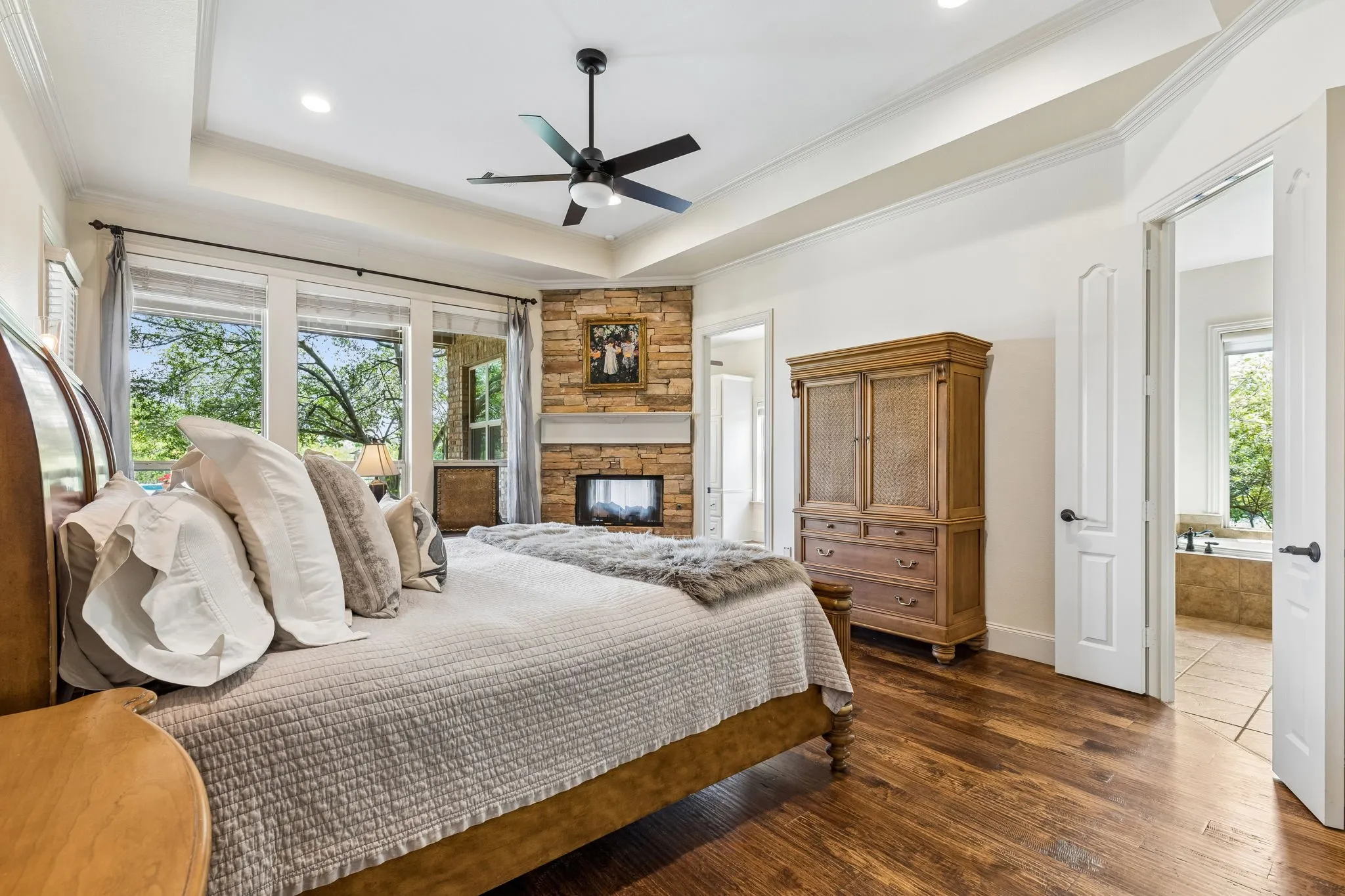 The property features wood flooring, a ceiling fan, and a stone fireplace