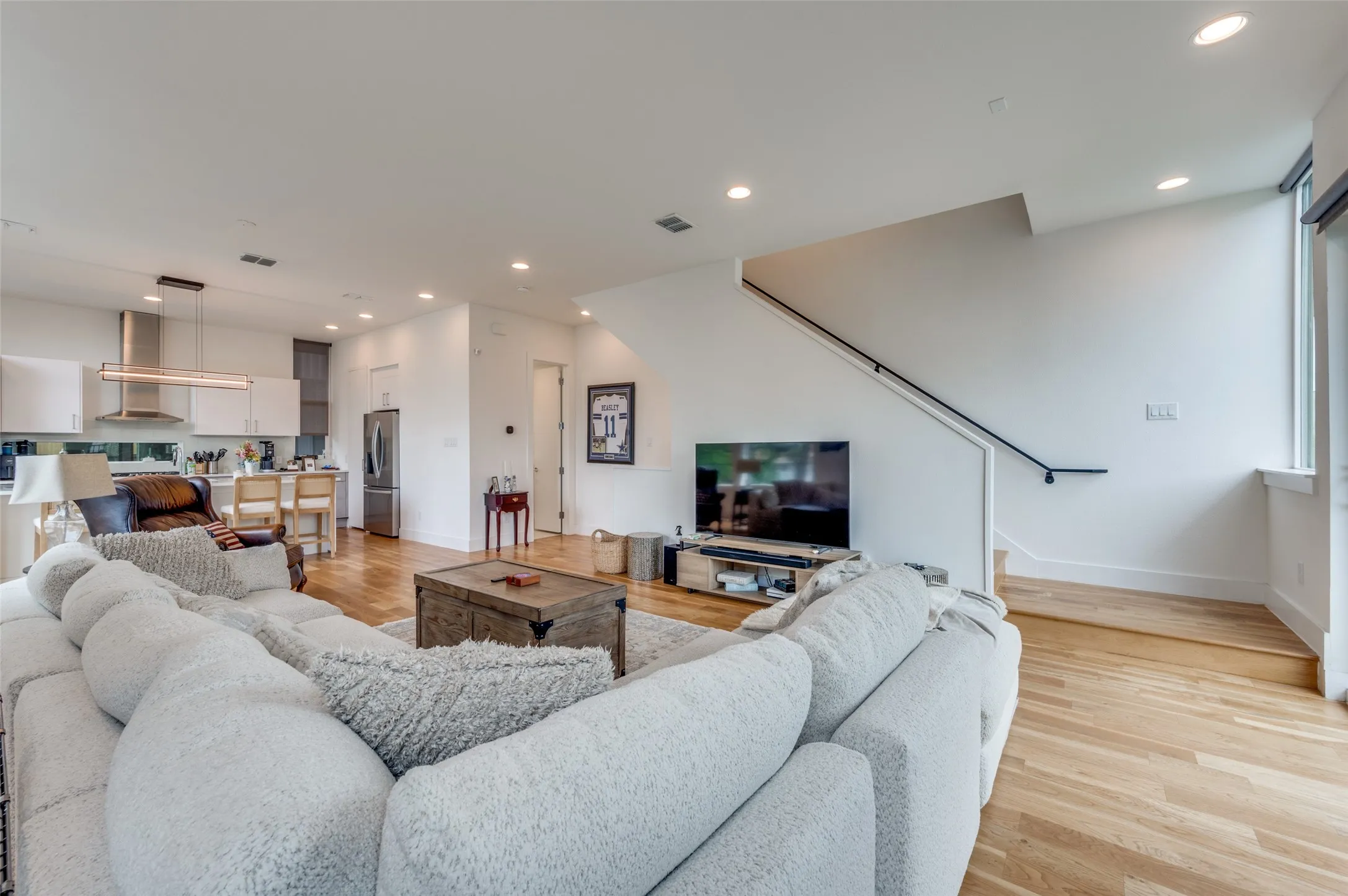 Open concept living area with hardwood flooring, recessed lighting, and a modern staircase