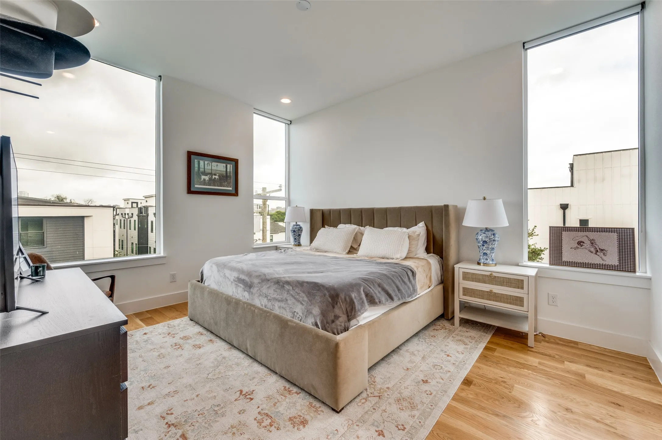 This room features light hardwood flooring, large windows providing ample natural light, and recessed lighting