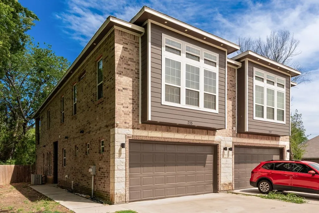 The property features a brick and stone facade with modern siding accents, and includes an integrated garage