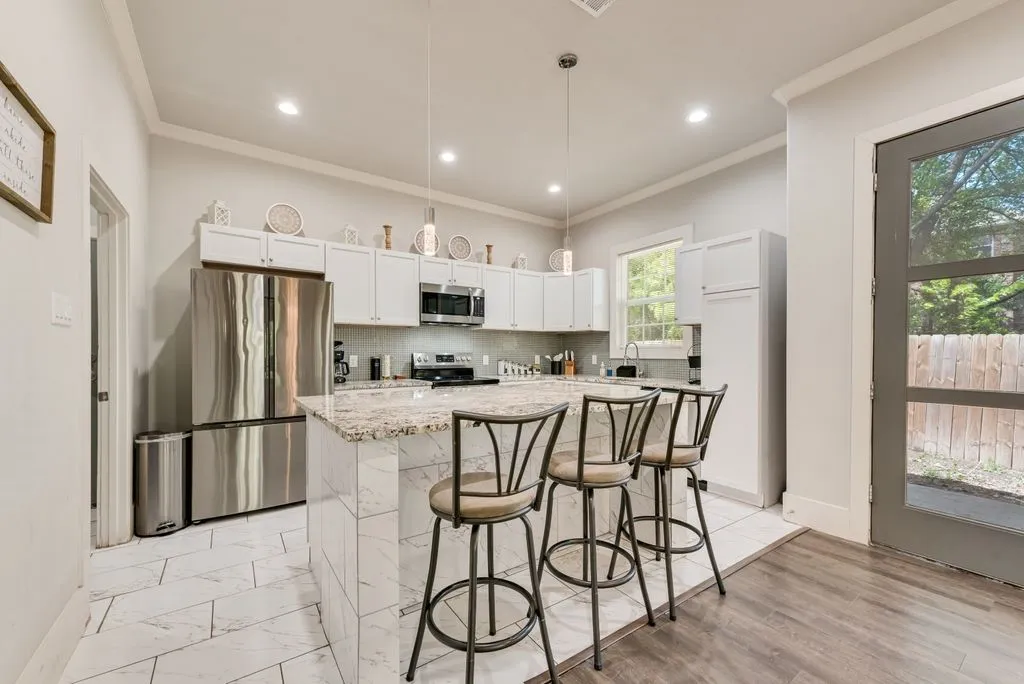 The kitchen features white cabinetry, stainless steel appliances, and an island with a light-colored countertop