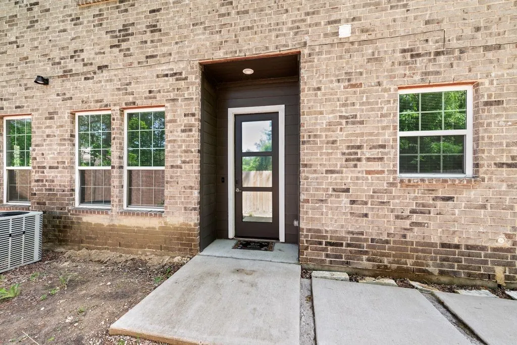 The property features an exterior of light brown brick with a dark brown entry door and white-framed windows