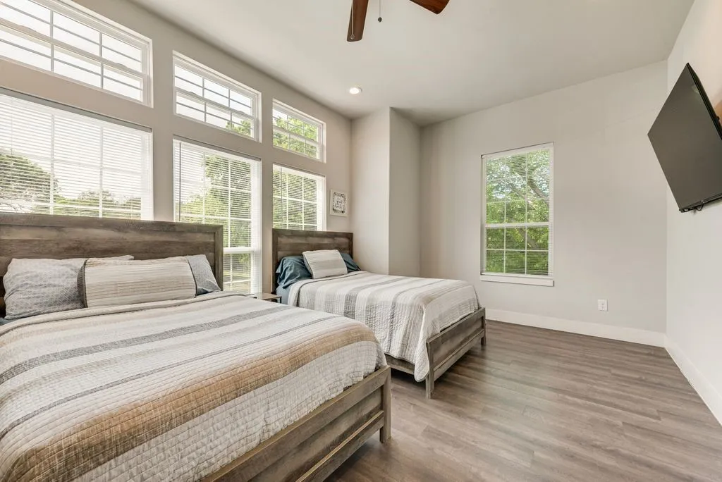 This room features extensive window coverage with both lower and upper windows, a ceiling fan, and durable wood-look flooring