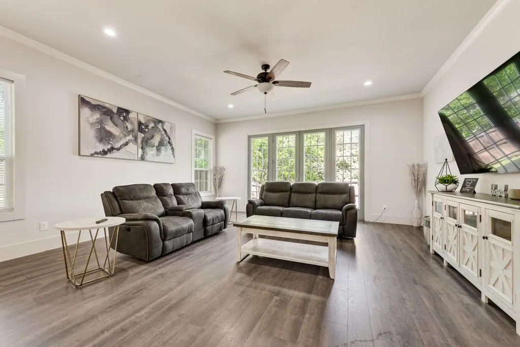 This living area features rich wood flooring, recessed lighting, and a ceiling fan