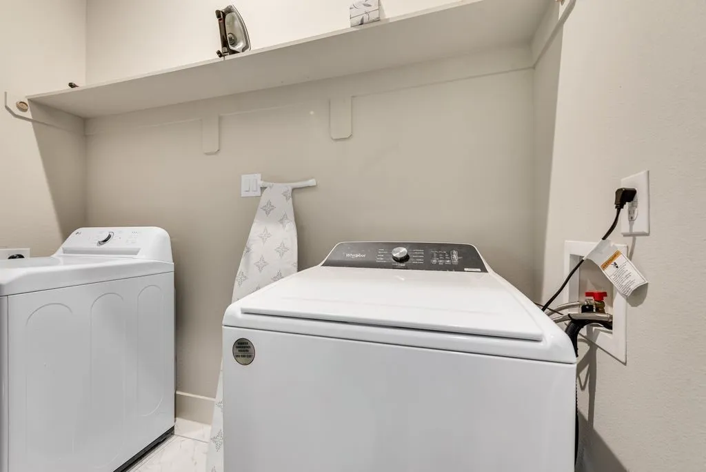 This utility space features a white top-loading washing machine and a white top-loading dryer