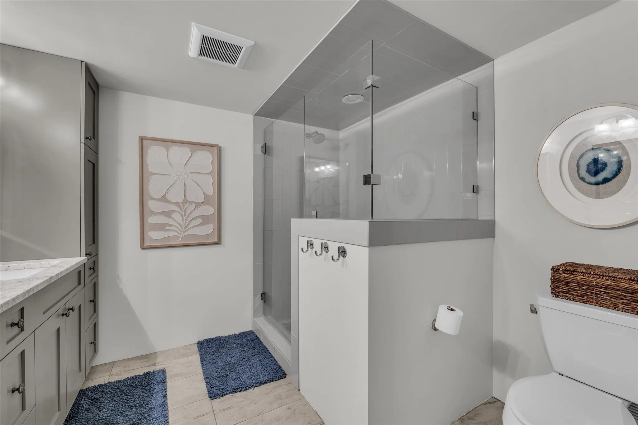 Full bathroom featuring double vanity, a stall shower, and light tile patterned flooring