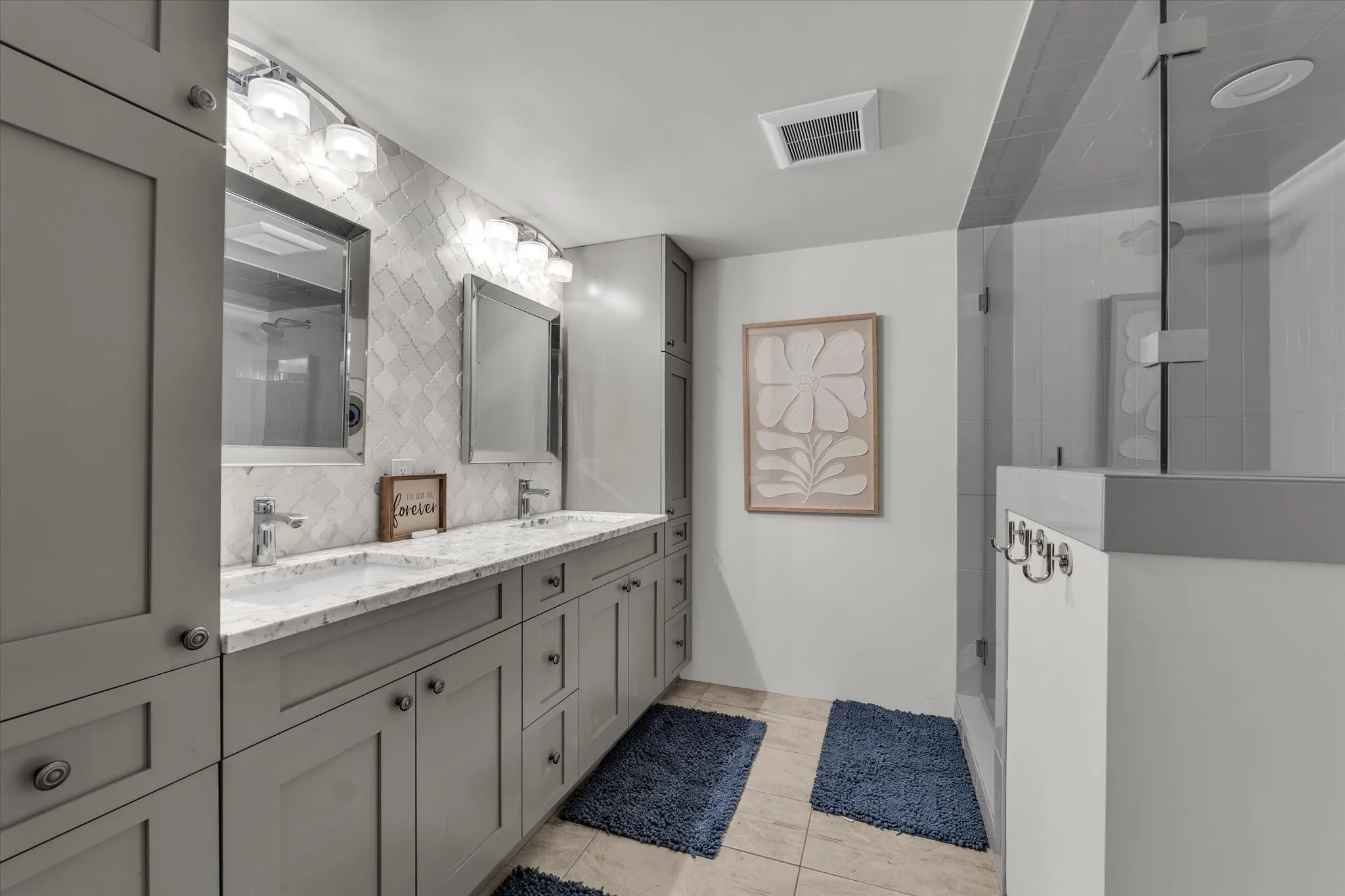 Bathroom with double vanity, a shower stall, light tile patterned flooring, and decorative backsplash