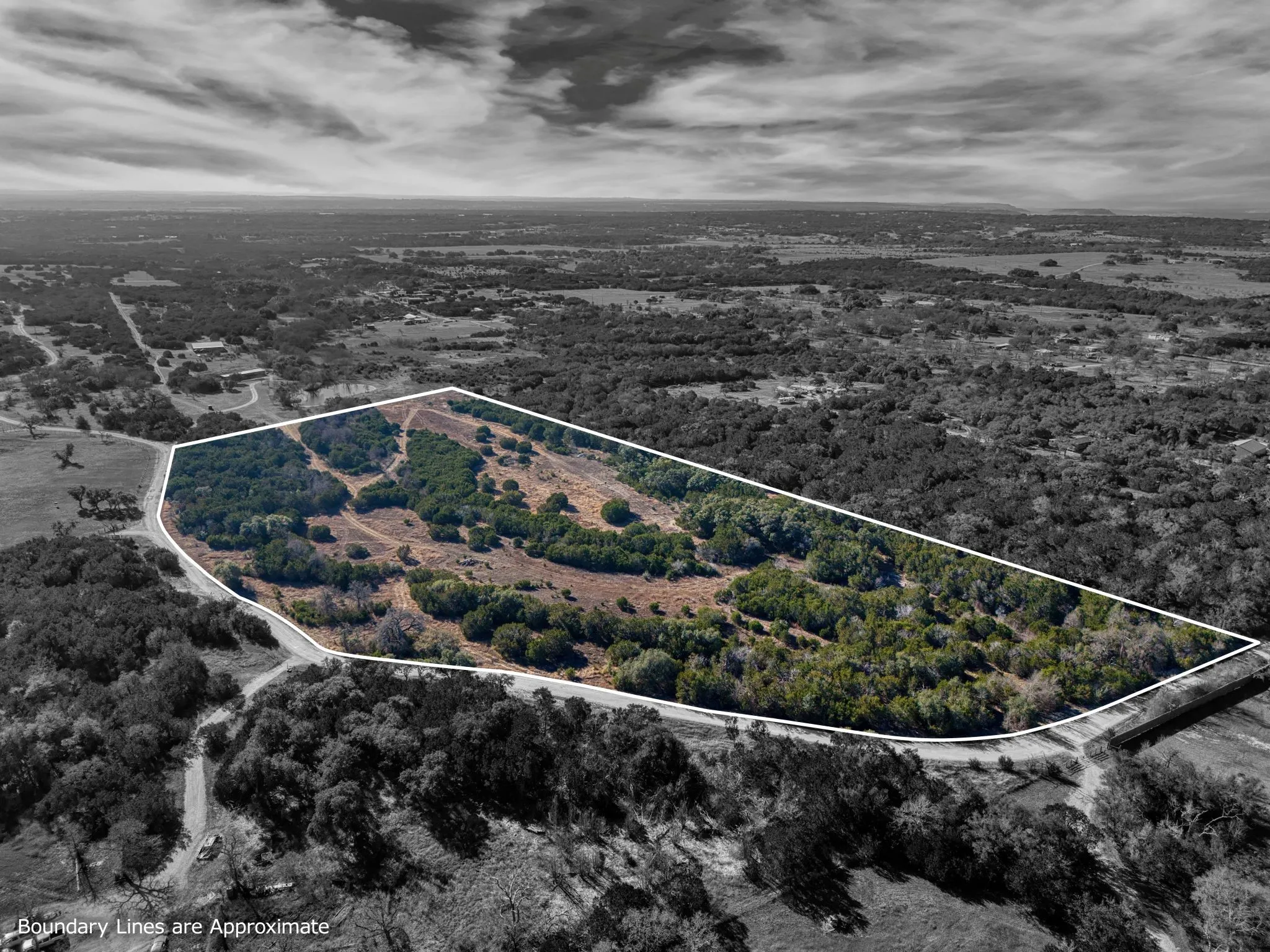 Aerial view showcasing the property's expansive, irregular-shaped lot, featuring a mix of mature trees and open land