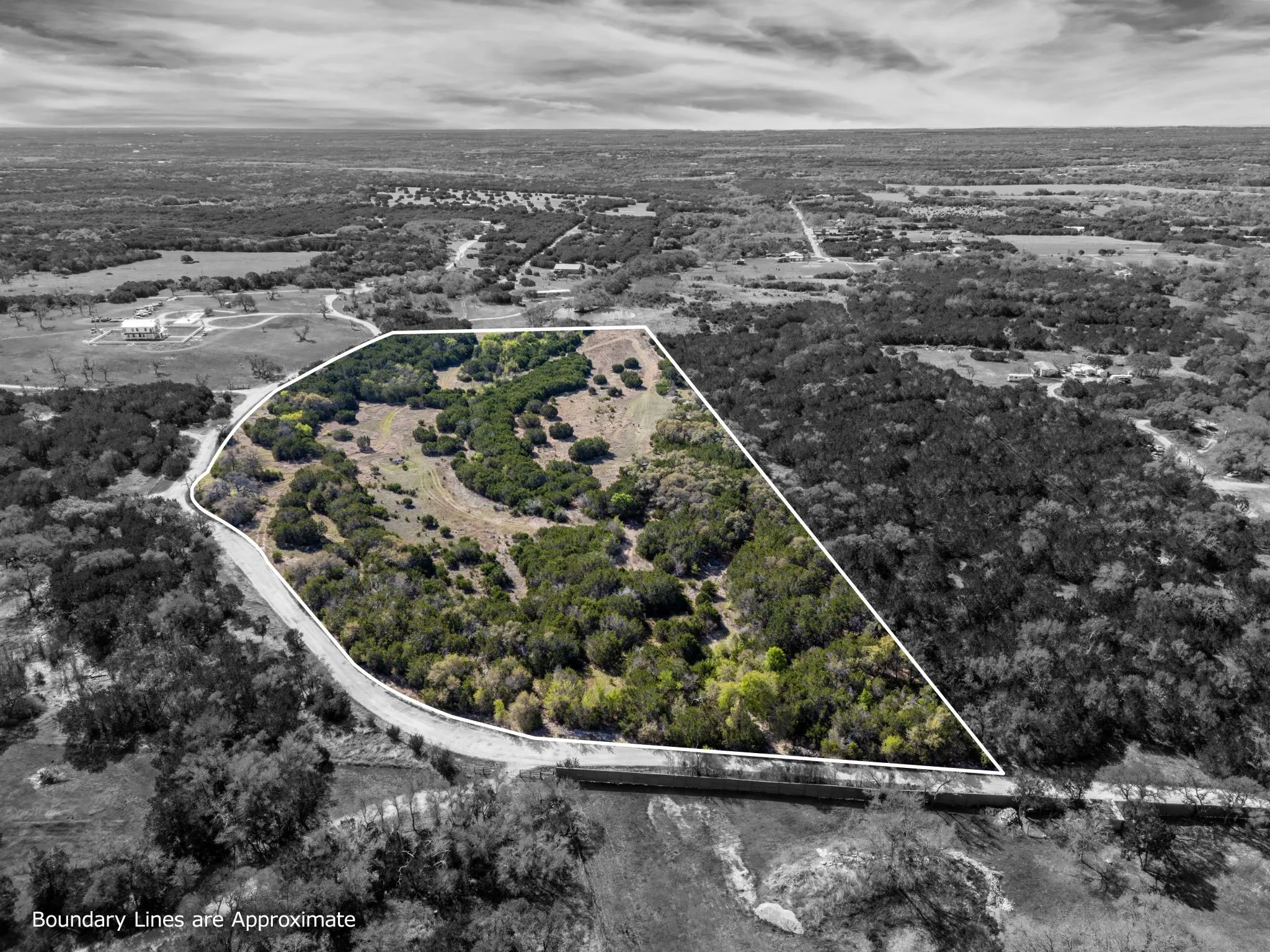 Aerial view showcasing the property's expansive, irregular-shaped lot, featuring a mix of mature trees and open land