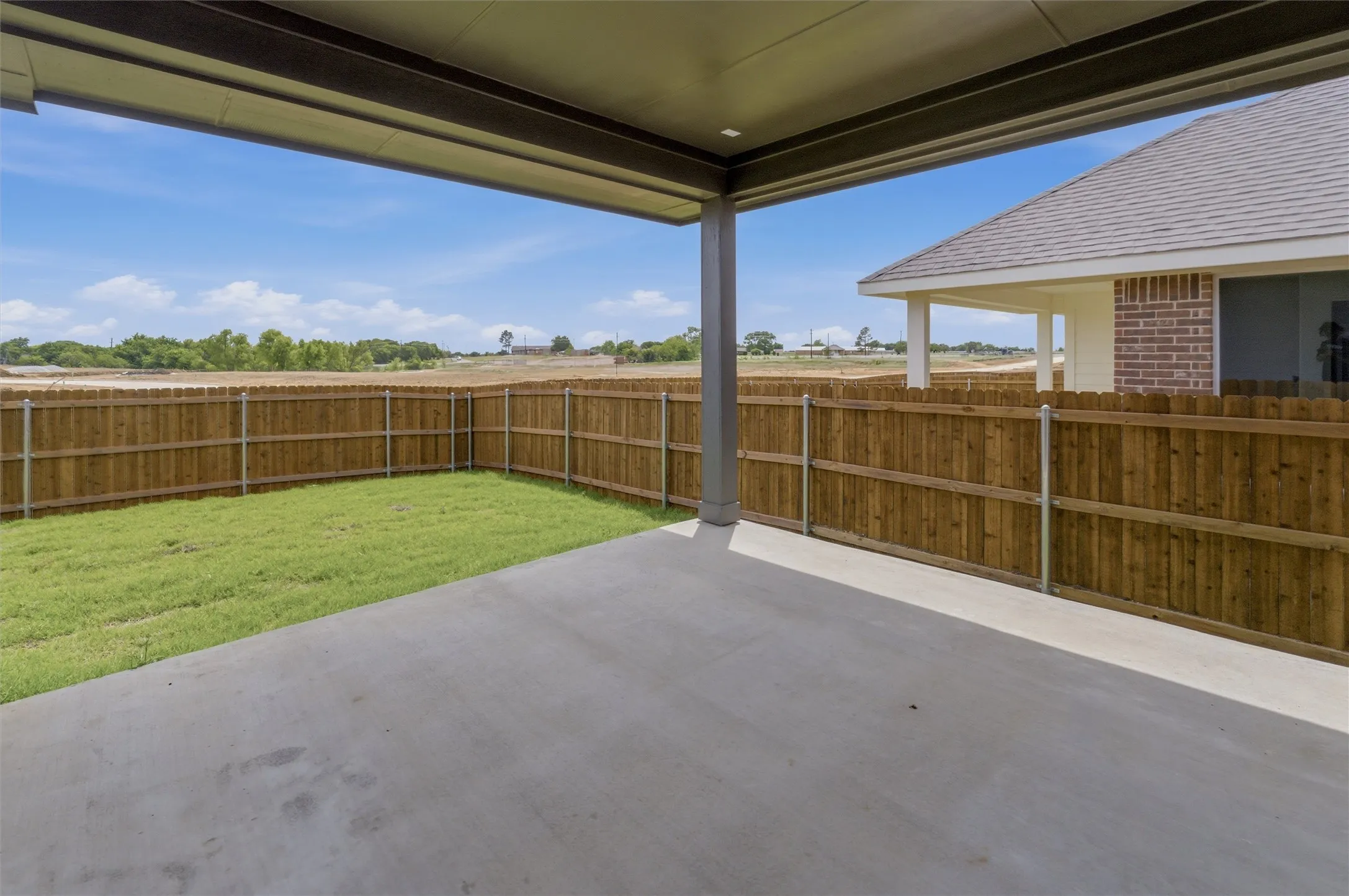 Covered patio with a concrete surface, enclosed by a wood privacy fence