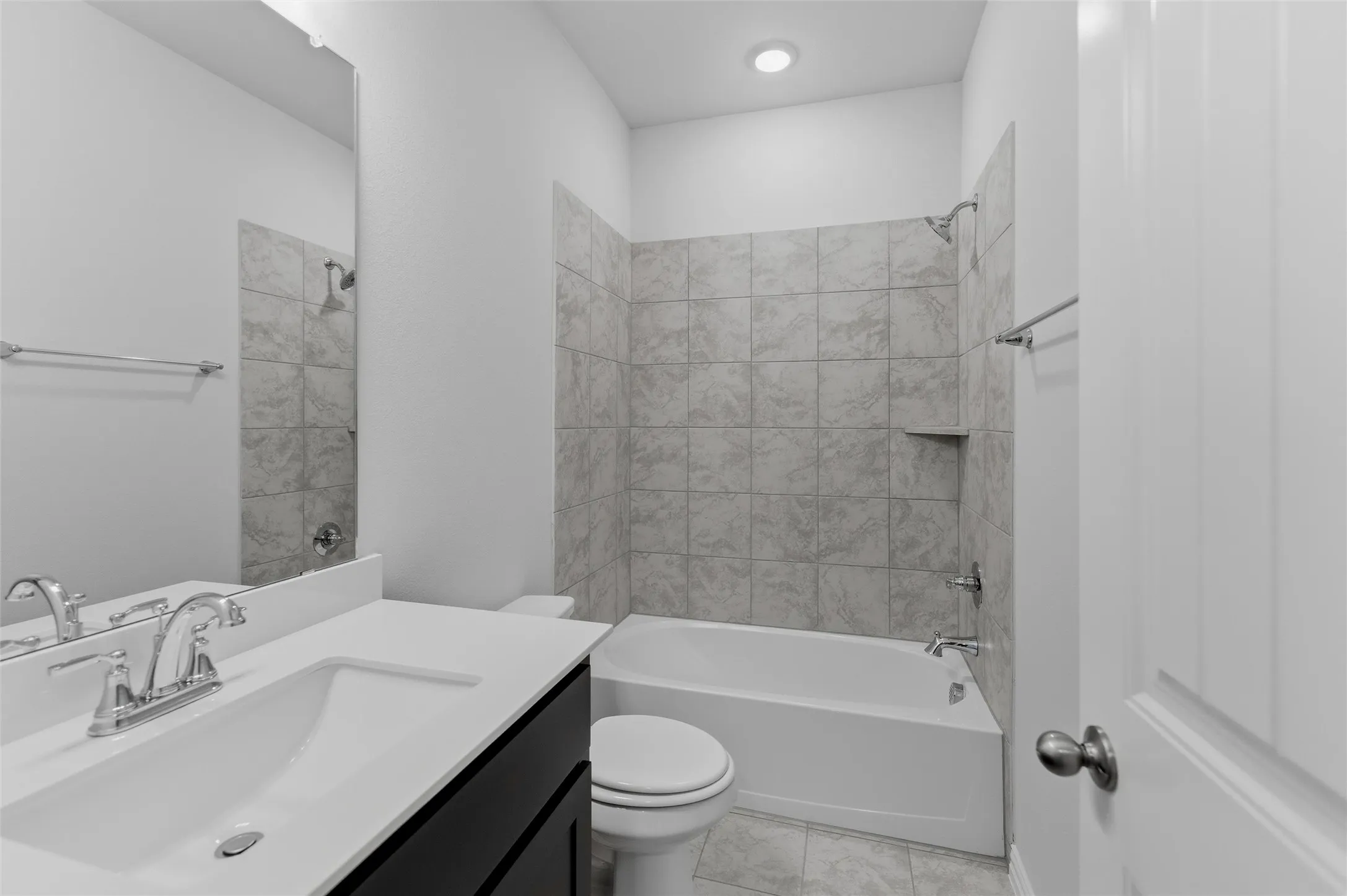 Bathroom featuring a single vanity with dark cabinetry and a white countertop, an undermount sink, and chrome fixtures