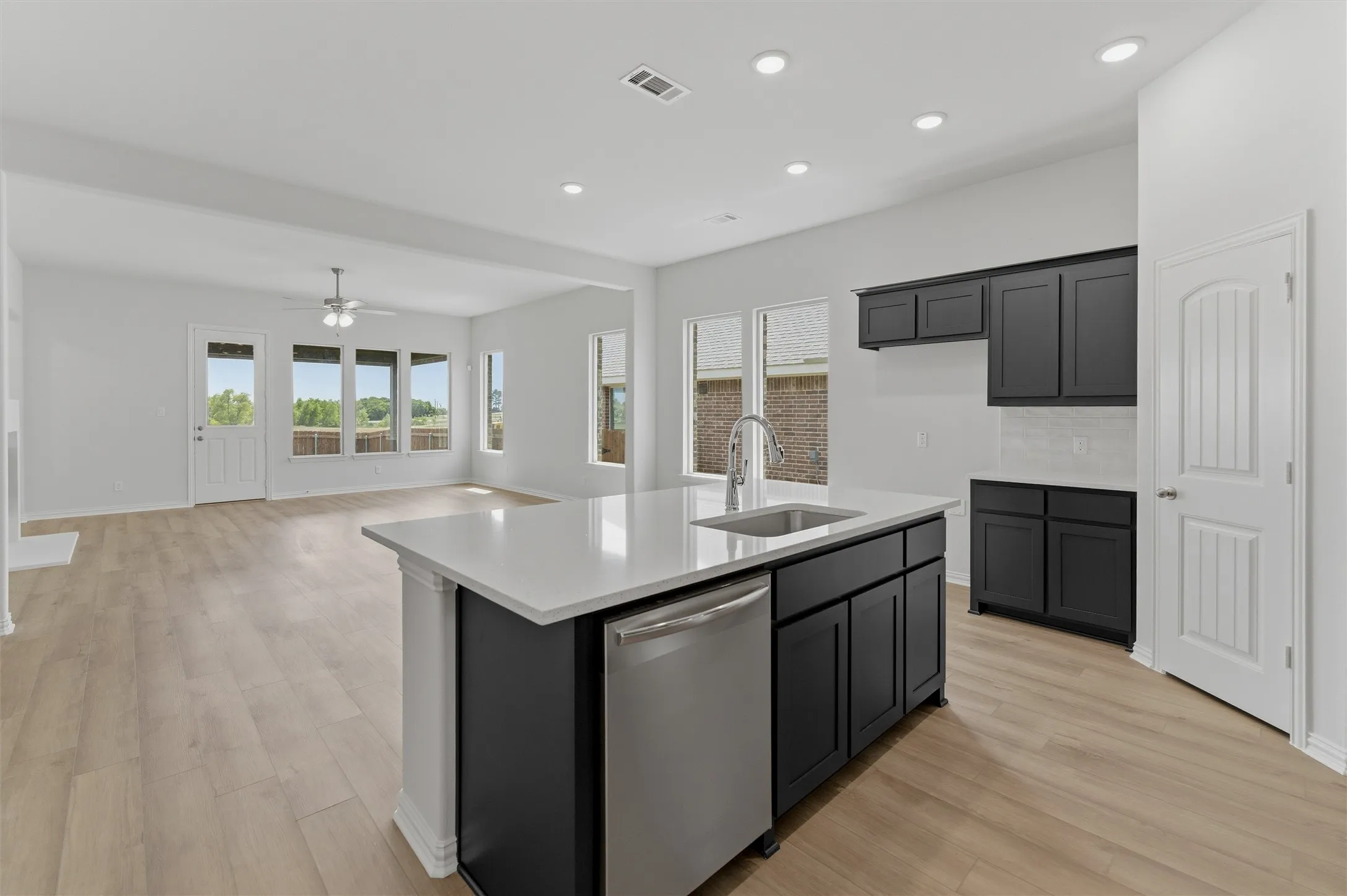 Kitchen island with white countertop, undermount sink, and stainless steel​​‌​​​​‌​​‌‌​‌‌​​​‌‌​‌​‌​‌​​​‌​​ dishwasher
